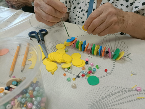 Zdjęcie_nr_8_przedstawia_zajęcia_z_arteterapii_podczas_których_seniorzy_tworzyli_kolorowe_breloki_z_pianki_i_koralików.png