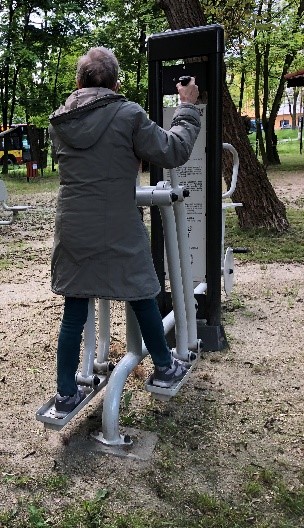 Fotografia Przedstawia Klientkę DDP podczas ćwiczeń na orbitreku znajdującym się w ogrodzie DDP